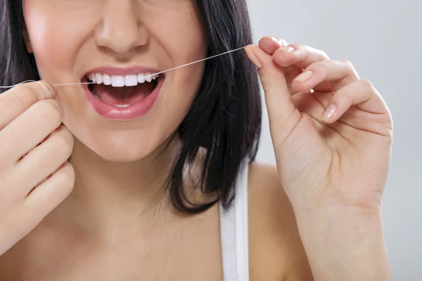 Close-up of a woman flossing his teeth with dental floss
