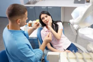 Girl patient goes to the dentist with a toothache in the dental office. Young woman holding the hand of a sick tooth
