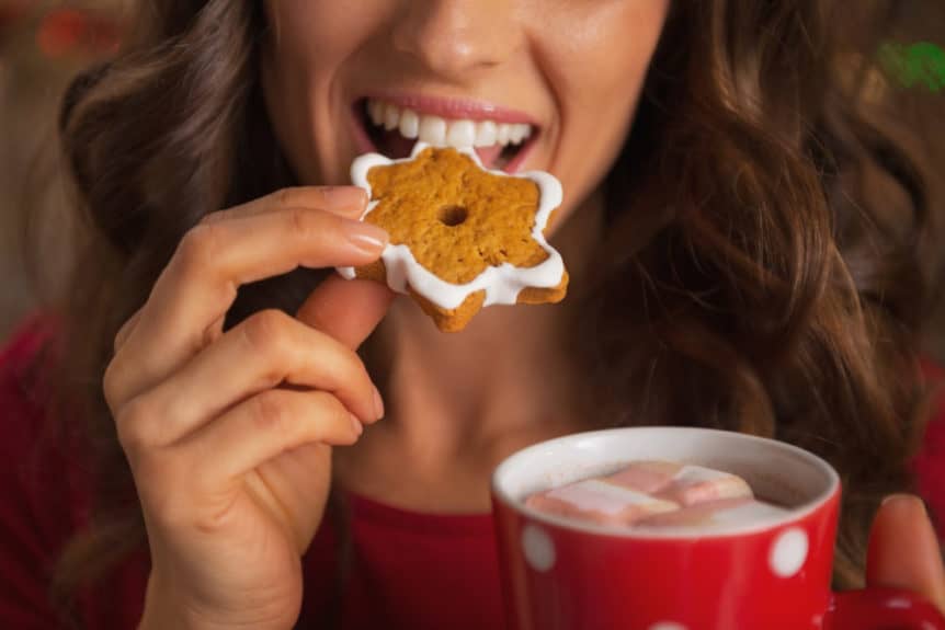 Closeup on happy young woman eating christmas cookie