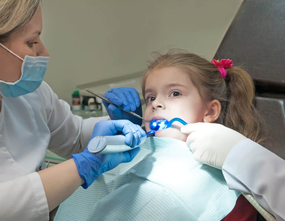 Mid section view of a dentist examining a girl teeth